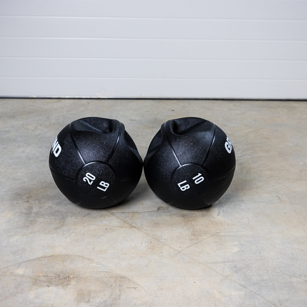 20lb and 10lb GRIND Dual-Grip Medicine Balls side by side on the floor.