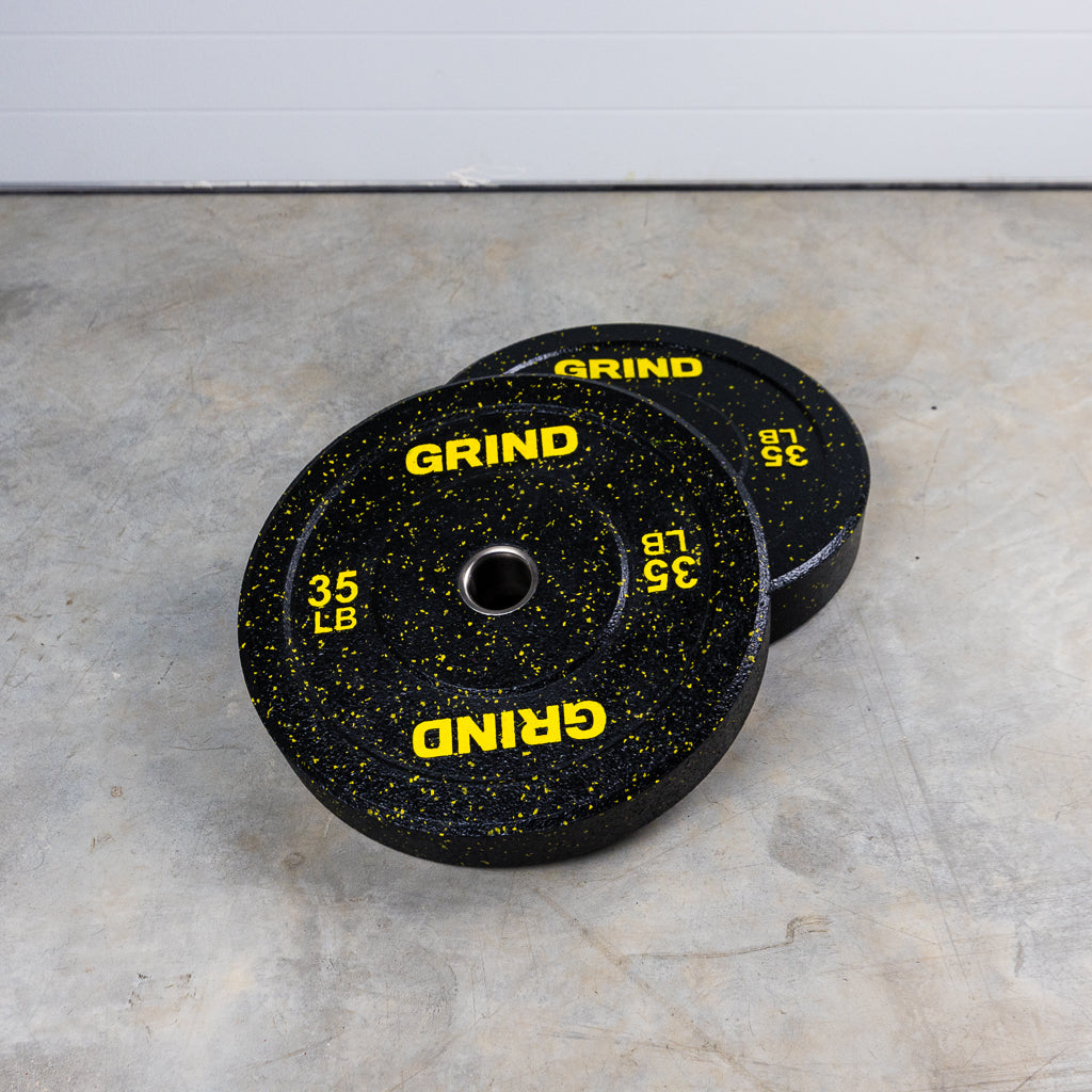 Yellow 35lb GRIND Fitness Black Carbon Weight Plates with Yellow Colored Fleck pieces on each plate.