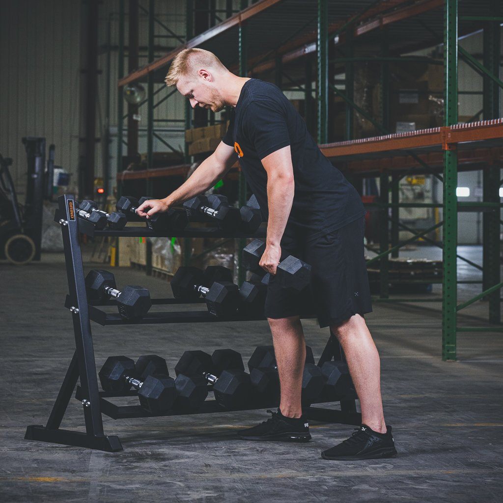 Standing and Lifting a Dumbbell Up Front of The GRIND Fitness Dumbbell Rack