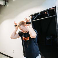 Thumbnail for Man demonstrating overhead tricep press using resistance band handles connected to Door Mounted Pull-Up Bar.