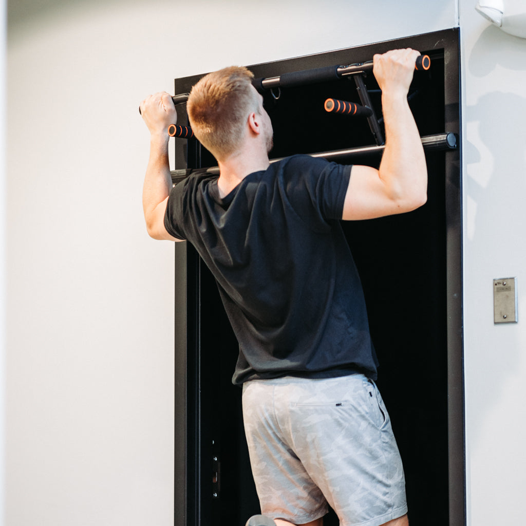 Man doing wide grip pull up on Door Mounted Pull-Up Bar.
