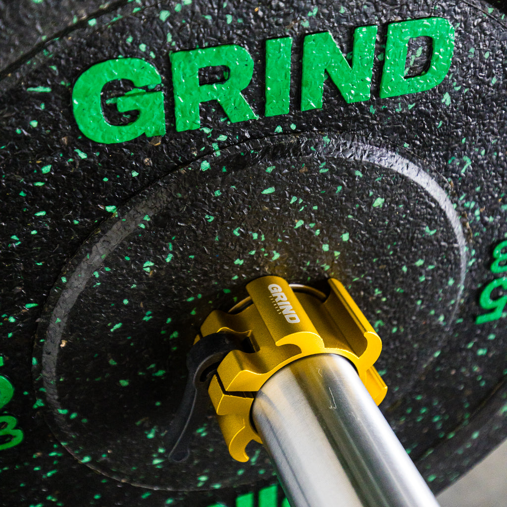 yellow GRIND gripper collar locked on a barbell with a crumb rubber GRIND weight plate