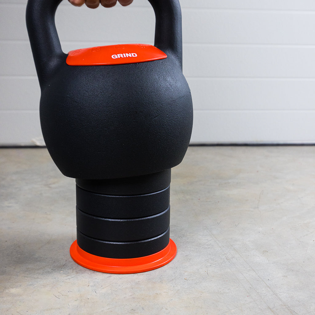 Person lowering the GRIND Adjustable Kettlebell onto a stack of weight inserts.