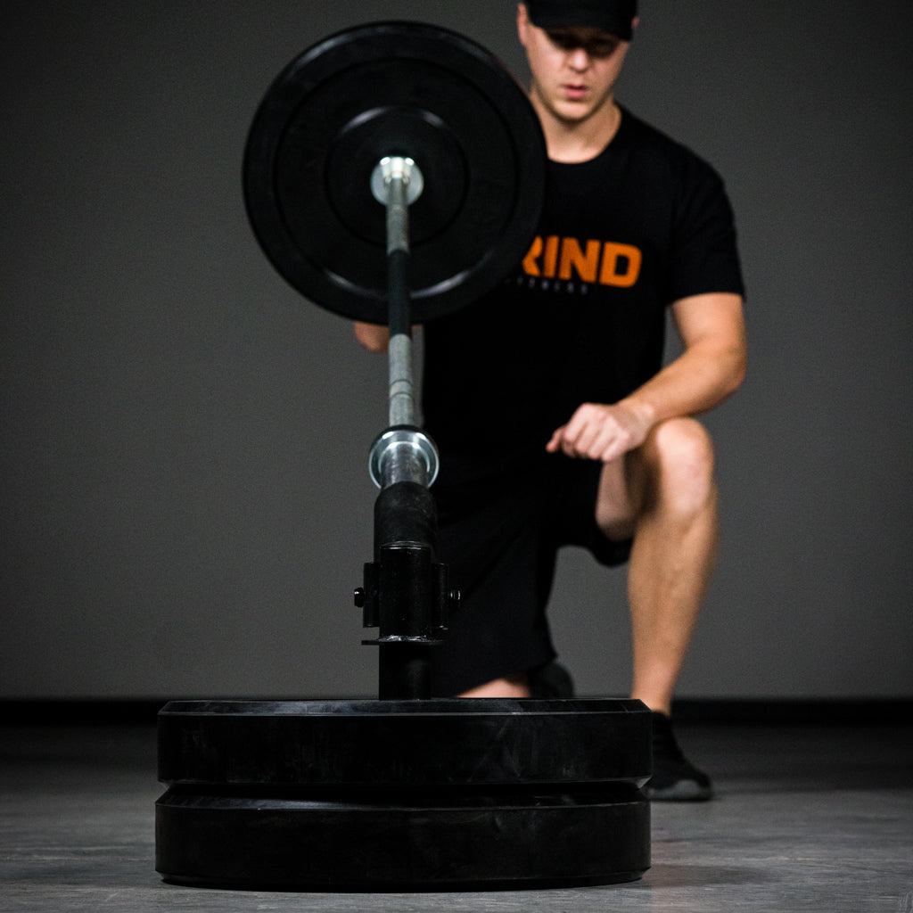 Man kneeling demonstrating upward thrust with landmine