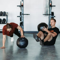 Thumbnail for Two people working out with Soft Wall Balls. One doing Russian twists and one using Soft Wall Ball for one arm elevated push up.