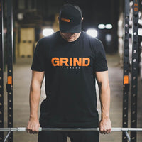 Thumbnail for The GRIND Fitness Black Tee Shirt with Orange and Grey Logo chest print.